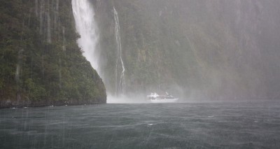 Wasserfall und Boot auf dem Wasser des Milford Sounds